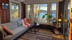 Ein gemütliches Zimmer mit einer Couch, einem kleinen Tisch und Seeblick.