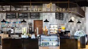 Un café-delicatessen con mostrador, máquinas de café y una vitrina con productos alimenticios.