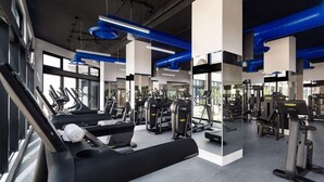 Ein modernes Fitnessstudio mit Laufbändern, Krafttrainingsgeräten und Spiegeln.