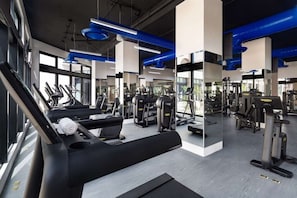 Academia moderna com esteiras, aparelhos de musculação e espelhos.