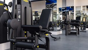 Un gimnasio con diversas máquinas de ejercicio, incluyendo máquinas para extensión de piernas y press de pecho.