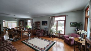 A spacious living room with hardwood floors, a large floral rug, and a dining area with wooden furniture. - Sweetfern Inn (Clare)