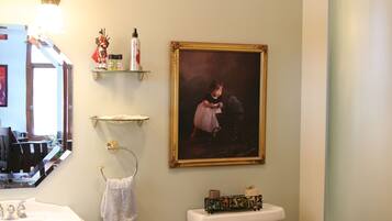 Un baño con lavamanos, inodoro y un cuadro enmarcado en la pared.
