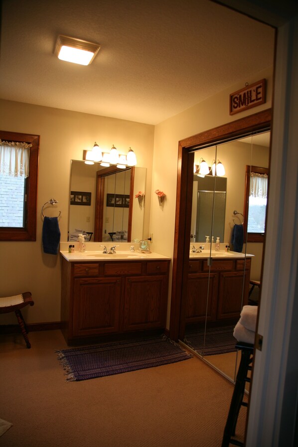 A bathroom with wooden cabinets, a large mirror, and a "SMILE" sign above the mirror. - Sweetfern Inn (Clare)