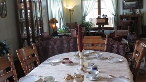 A dining room with a round table set for four, surrounded by wooden chairs. - Sweetfern Inn (Clare)