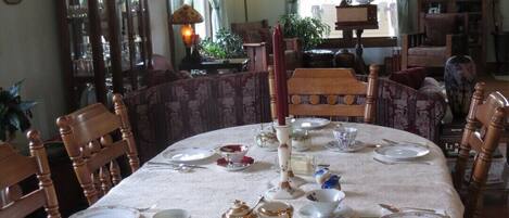 A dining room with a round table set for four, surrounded by wooden chairs.