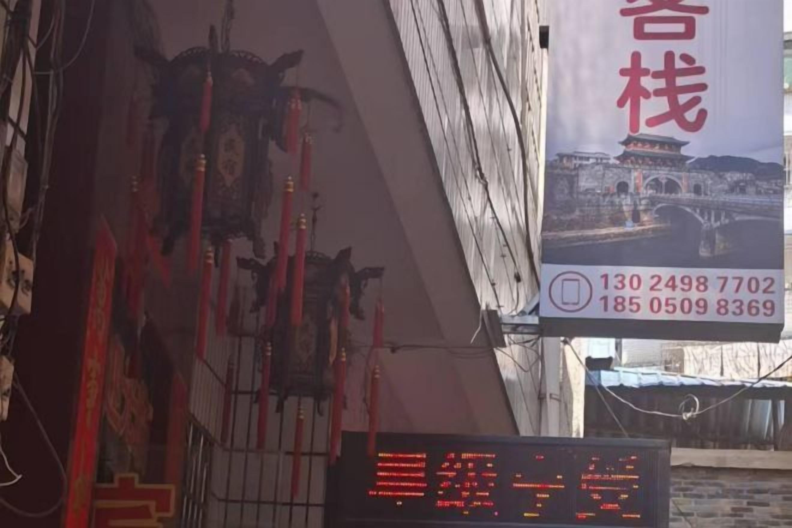 A hotel interior with a digital display board, red decorations, and a banner with contact information.