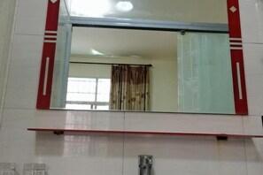 Une salle de bain avec un grand miroir, une douche et des toilettes.