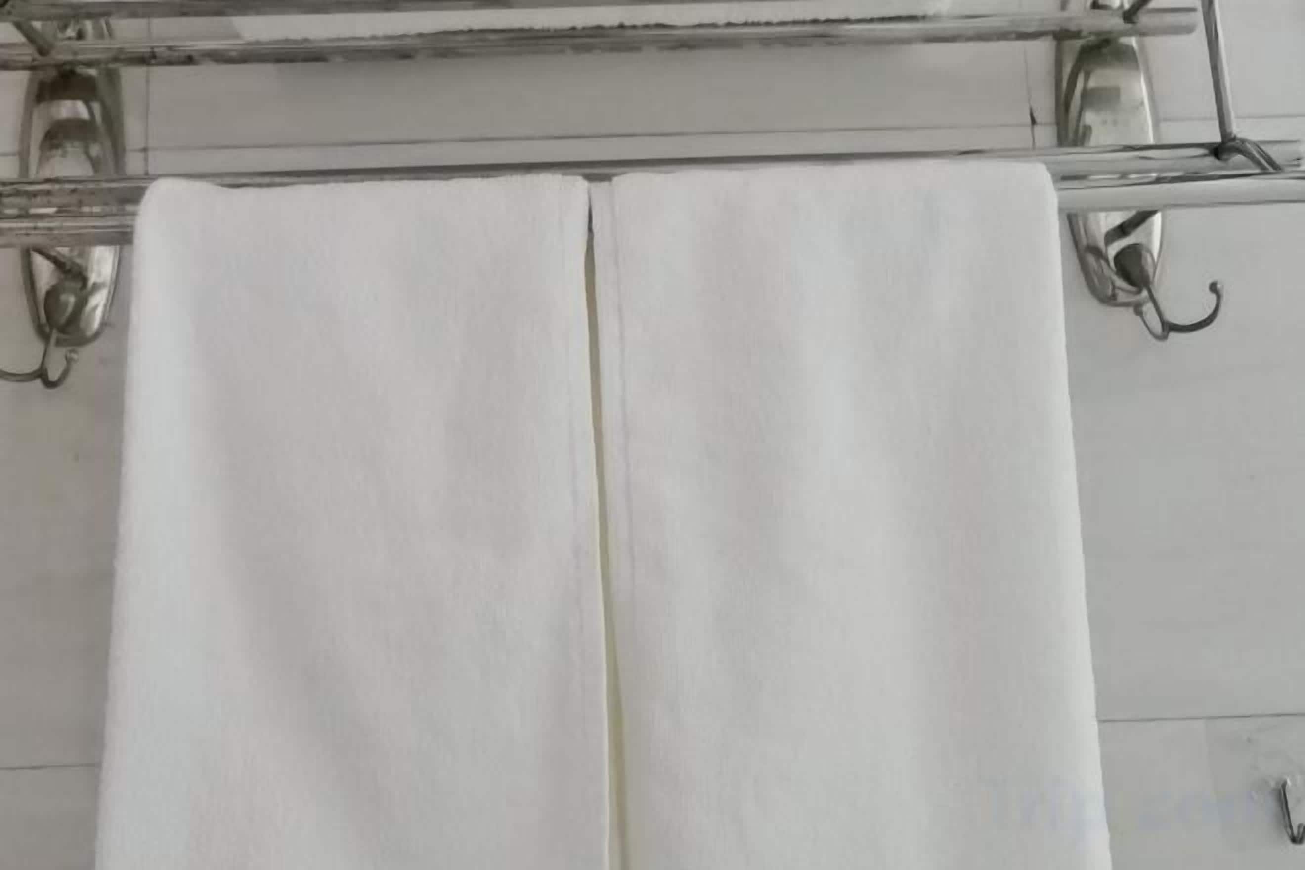 Une serviette blanche est suspendue à un porte-serviettes en métal dans une salle de bain.