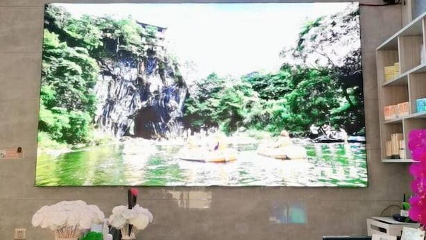 A large wall-mounted TV displaying a scenic waterfall and greenery.
