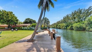 A wooden dock extending over a calm river, surrounded by lush greenery and palm trees. - Spacious 6-bedroom villa - with Outdoor Oasis - Pool in charming Fort Lauderdale (Fort Lauderdale)