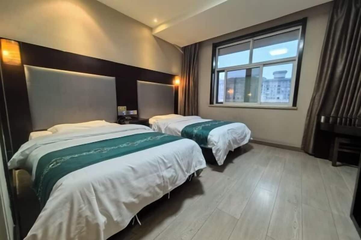 A hotel room with two beds, a large window with a city view, and a modern headboard.