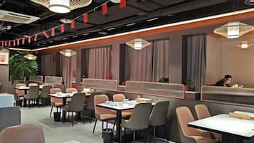 A modern restaurant interior with booths, tables, and hanging lights.