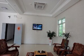 Un vestíbulo de hotel con televisor, zona de estar y una puerta que da a otra habitación.