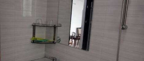 A bathroom with a sink, mirror, and shower.