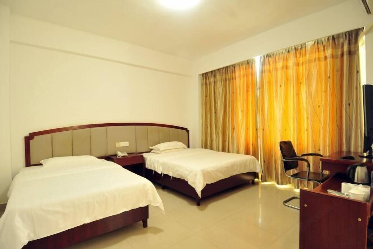 Une chambre d’hôtel avec deux lits, un bureau, une chaise et un téléviseur.