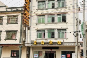 Un edificio de varios pisos, con un letrero con caracteres chinos y una entrada visible.