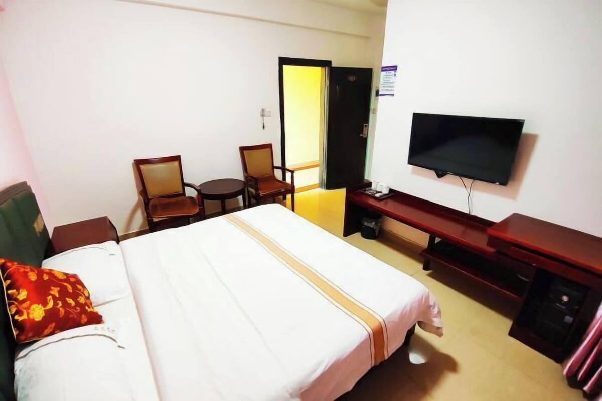 Une chambre d’hôtel avec un lit, un bureau, une chaise, une télévision et une porte.