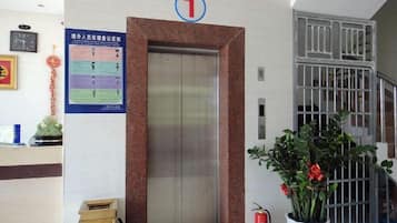 Un ascensor con un cartel del número 1, un extintor y una planta en maceta.