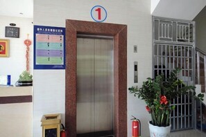 Un ascenseur avec un panneau indiquant le numéro 1, un extincteur et une plante en pot.