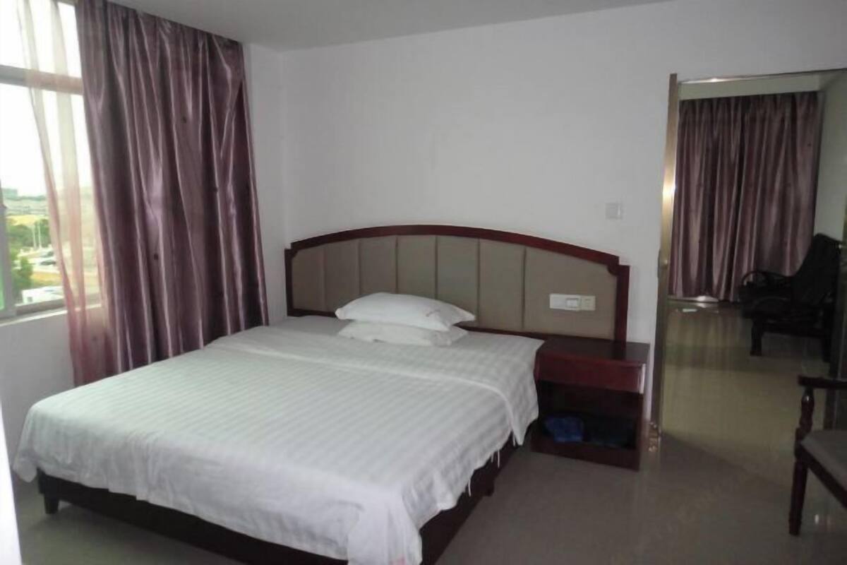 Une chambre d’hôtel avec un lit, une table de chevet, un miroir et une vue sur l’extérieur.