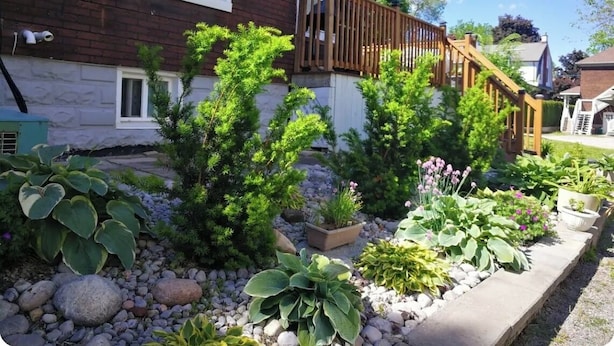 A residential house with a wooden deck, a stone pathway, and various potted plants. - **Riverview cottage** perfect for family vacation (Niagara Falls)