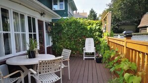 A wooden deck with a white table and chairs, surrounded by a wooden fence and greenery. - **Riverview cottage** perfect for family vacation (Niagara Falls)