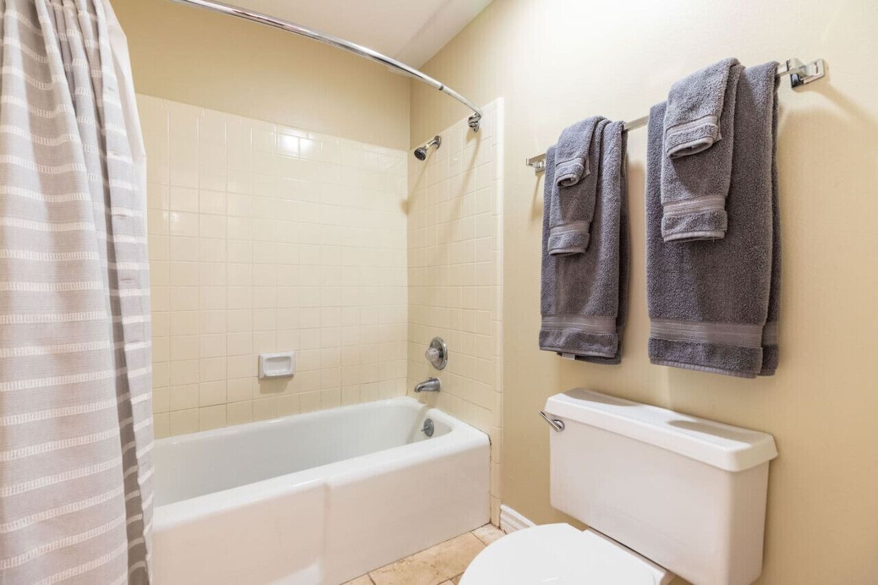 Une salle de bain avec une baignoire, une douche et des toilettes. Deux serviettes sont accrochées au mur.