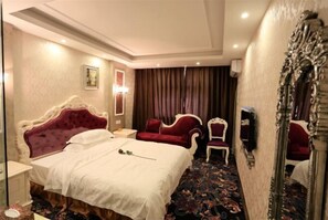 Ein Hotelzimmer mit einem großen Bett, zwei Sesseln, einem Spiegel und einem Teppichboden.