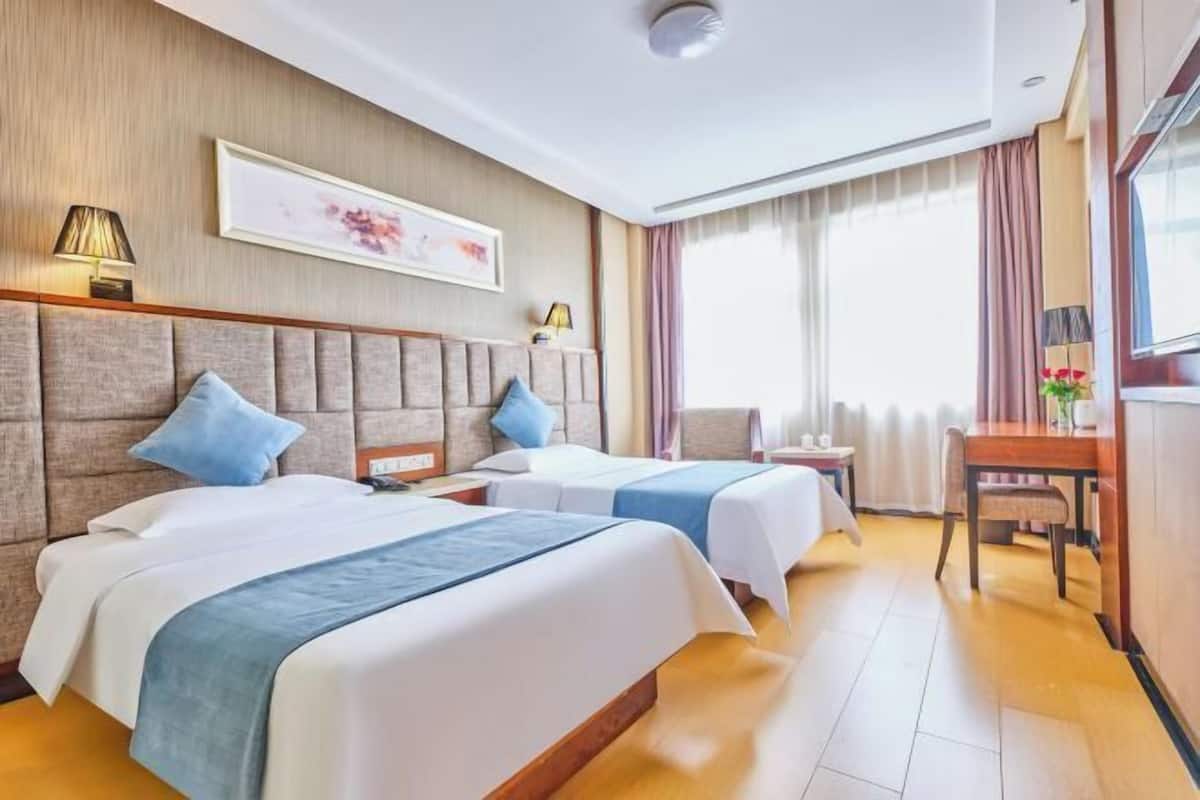 Une chambre d’hôtel avec deux lits, un bureau et une chaise.