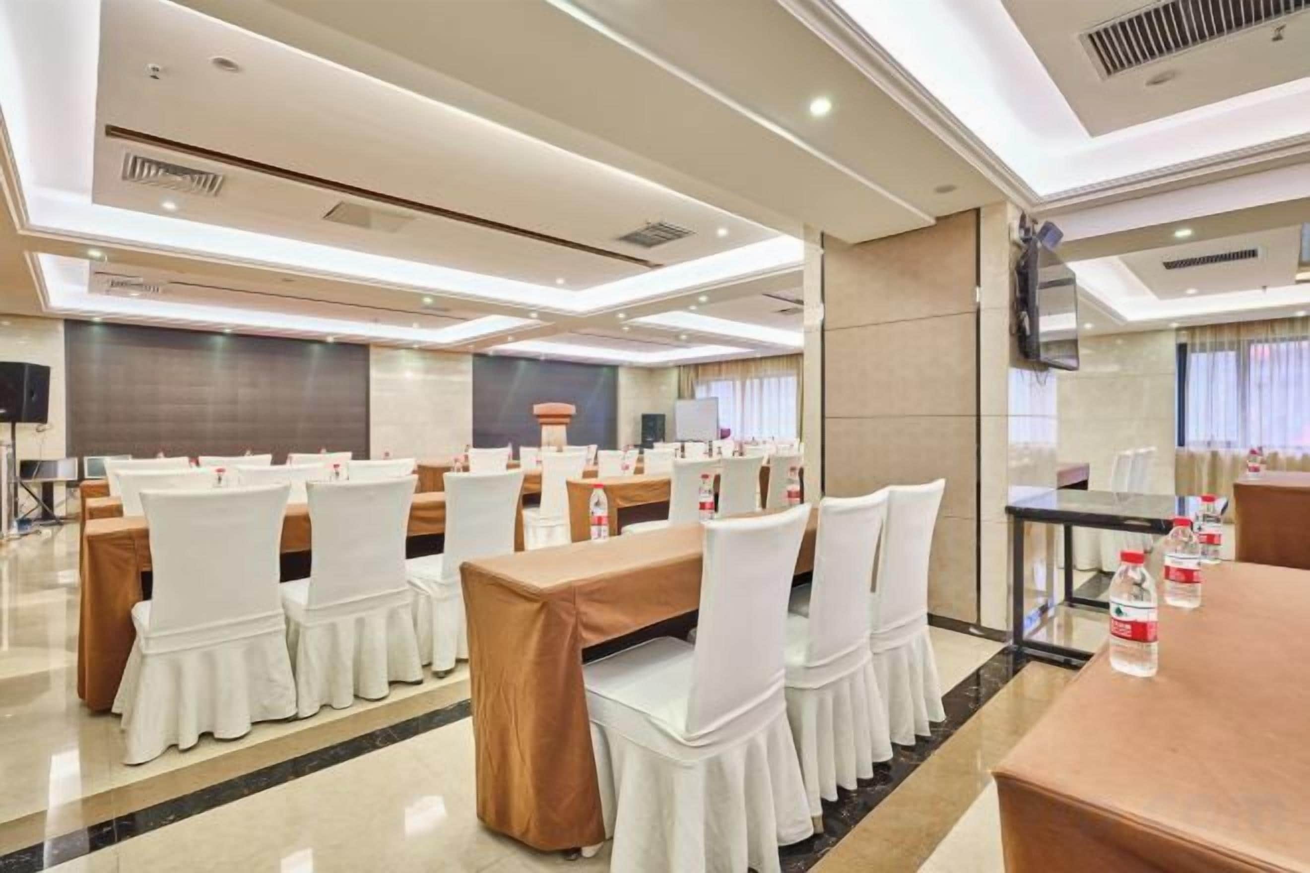 A conference room with tables and chairs, a television, and a large screen.