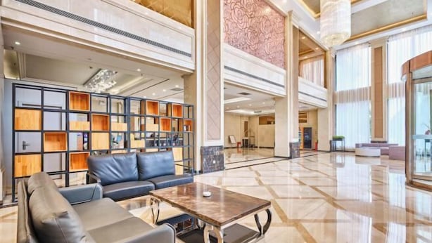 A spacious lobby with a modern design, featuring a large seating area with sofas and a coffee table, a bookshelf, and a decorative wall. - Runxi Yueju Hotel (Zhengzhou Erqi Wanda Plaza) (Zhengzhou)