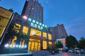 A hotel with a prominent entrance, multiple floors, and illuminated signage.