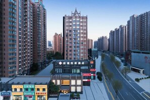 A high-rise building with a prominent central tower, surrounded by other high-rise buildings. - Runxi Yueju Hotel (Zhengzhou Erqi Wanda Plaza) (Zhengzhou)