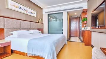 Habitación de hotel con cama, mesita de noche y vista al pasillo.
