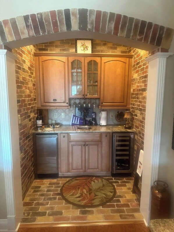A kitchen with brick walls, wooden cabinets, and a stone backsplash.