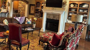Un salon chaleureux avec une cheminée, des fauteuils confortables et un téléviseur fixé au-dessus.
