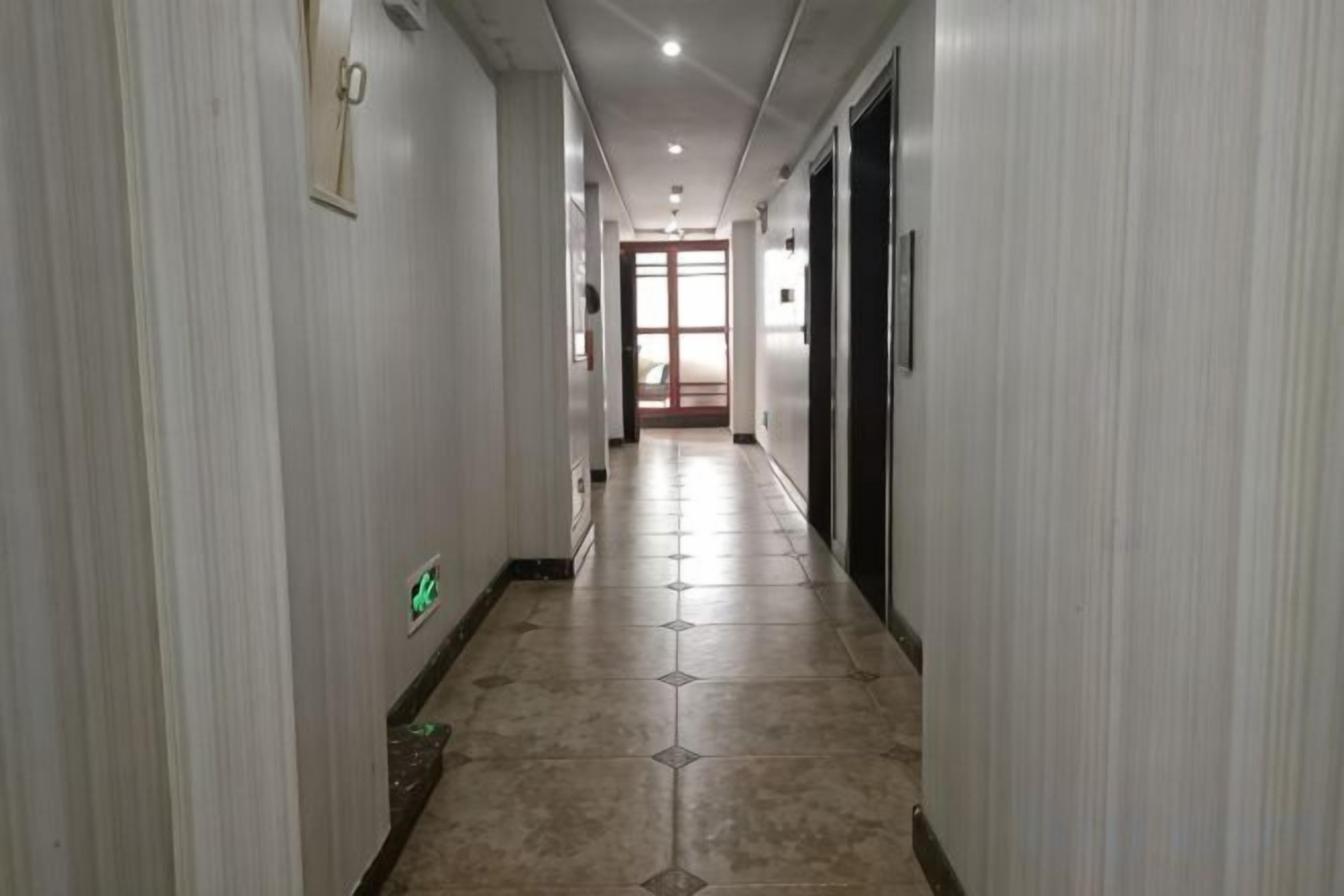 A hallway with a tiled floor, doors on both sides, and a light fixture on the ceiling.