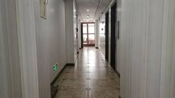 A hallway with a tiled floor, doors on both sides, and a light fixture on the ceiling.