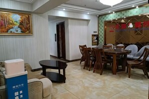 A hotel room with a dining area, a sofa, a table, and a painting on the wall.
