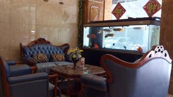 A seating area with a fish tank, blue upholstered chairs, and a decorative table.