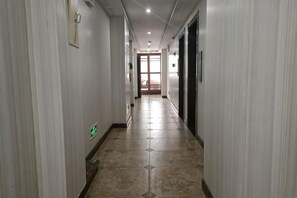 A hallway with a tiled floor, doors on both sides, and a light fixture on the ceiling.