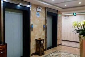 A hotel lobby with elevators, a reception desk, and a decorative plant. - Hefeng Pingjing Homestay (Hefeng)