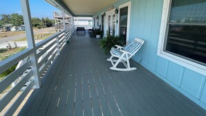 A covered porch with a bench and a rocking chair, a small table, and potted plants. - Perdido Key Water View with Pool, Second Floor Duplex (Pensacola)