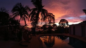 Panorama al tramonto con palme e piscina.