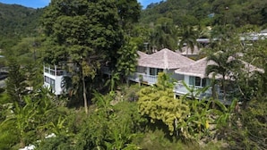 Un resort con diversi edifici in stile bungalow immerso in una lussureggiante vegetazione e circondato da colline.