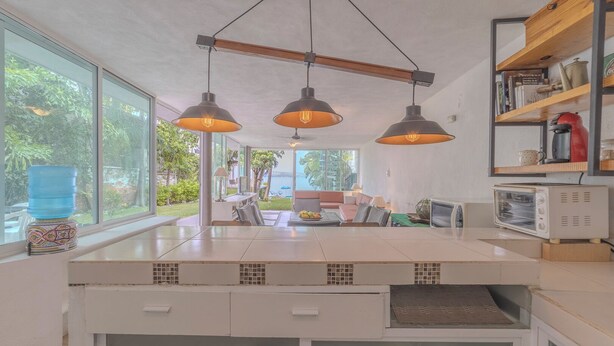 A modern kitchen with a large island, pendant lighting, and a view of the outdoors.