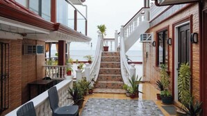 A hotel corridor with a staircase leading to the upper floor, potted plants, and a view of the sea. - RedDoorz Plus @ Billys Resort Oslob (Oslob)