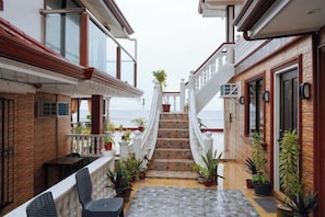 A narrow outdoor corridor with a staircase leading to a balcony, surrounded by potted plants and a seating area. - RedDoorz Plus @ Billys Resort Oslob (Oslob)