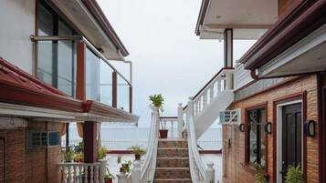 A narrow corridor with a staircase leading to a balcony overlooking the sea.